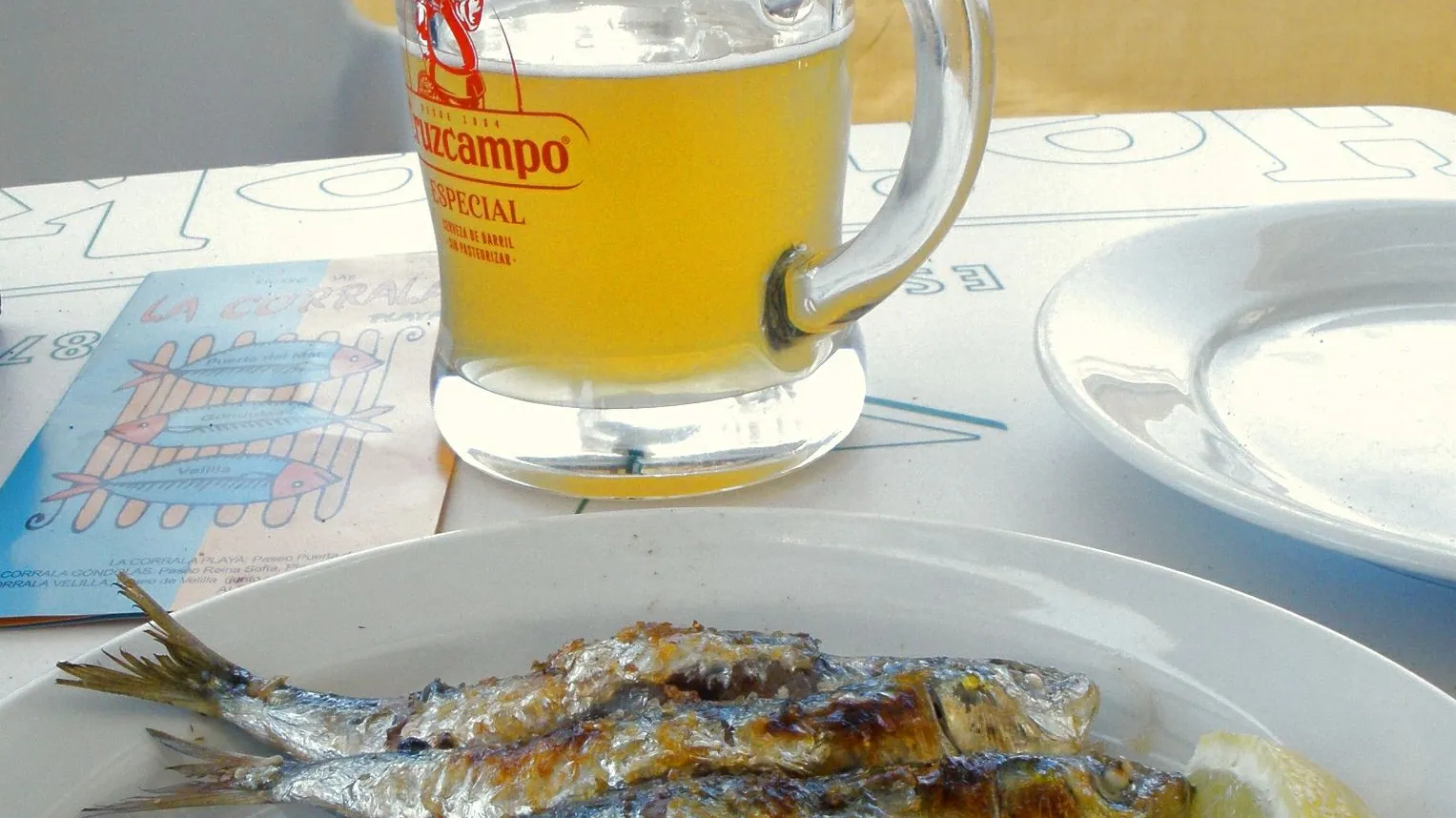 Sardines grilling on an espeto over a wood fire