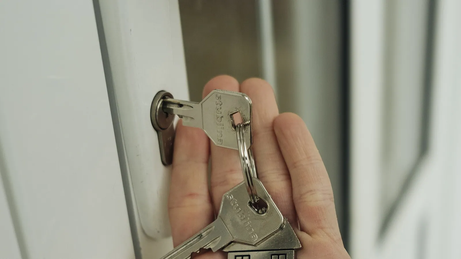 Une main tenant des clés de maison devant une porte